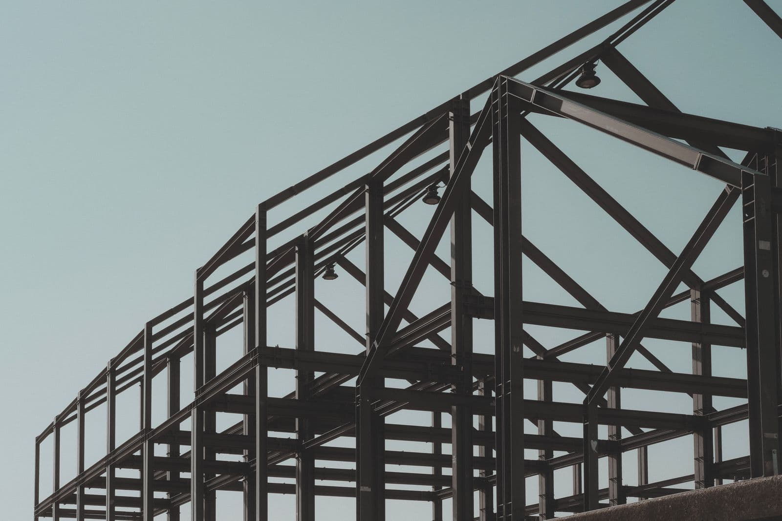 Structural steel frame of a large industrial building under construction against a clear sky