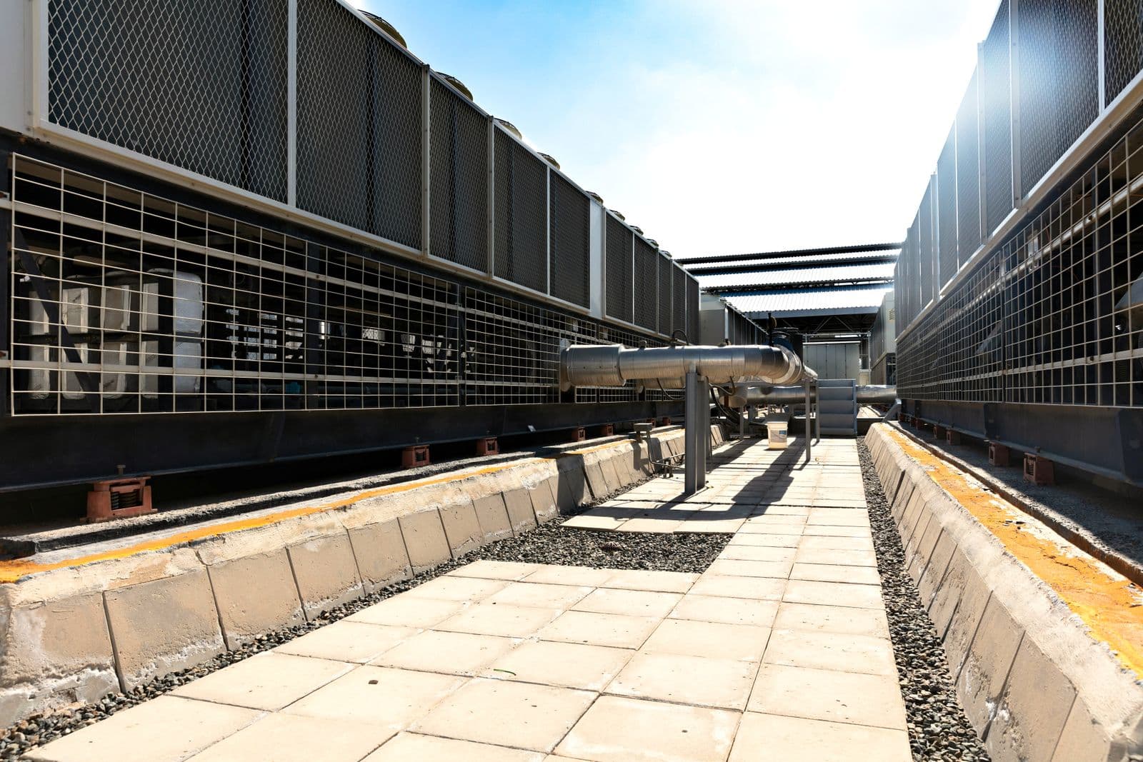 Rows of air cooled chiller units and connecting pipework in a data center cooling plant yard