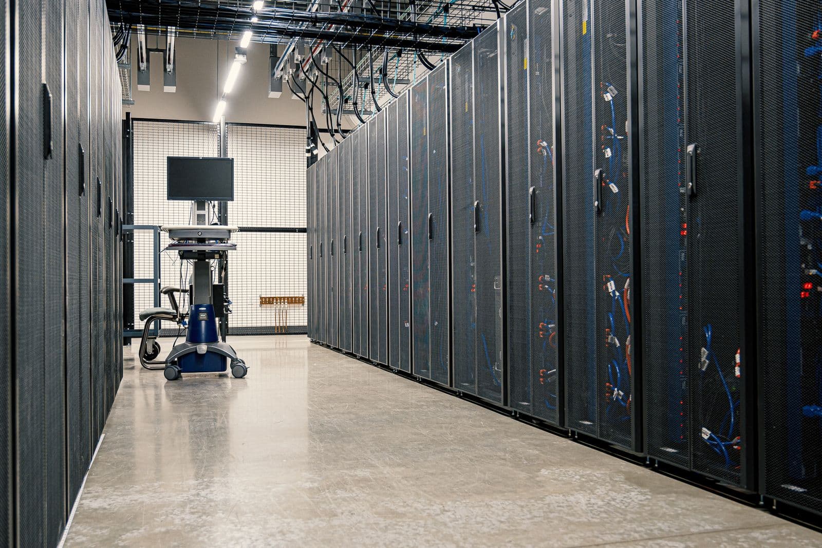 Aisle of high density racks with overhead containment and structured cabling in a live data center hall